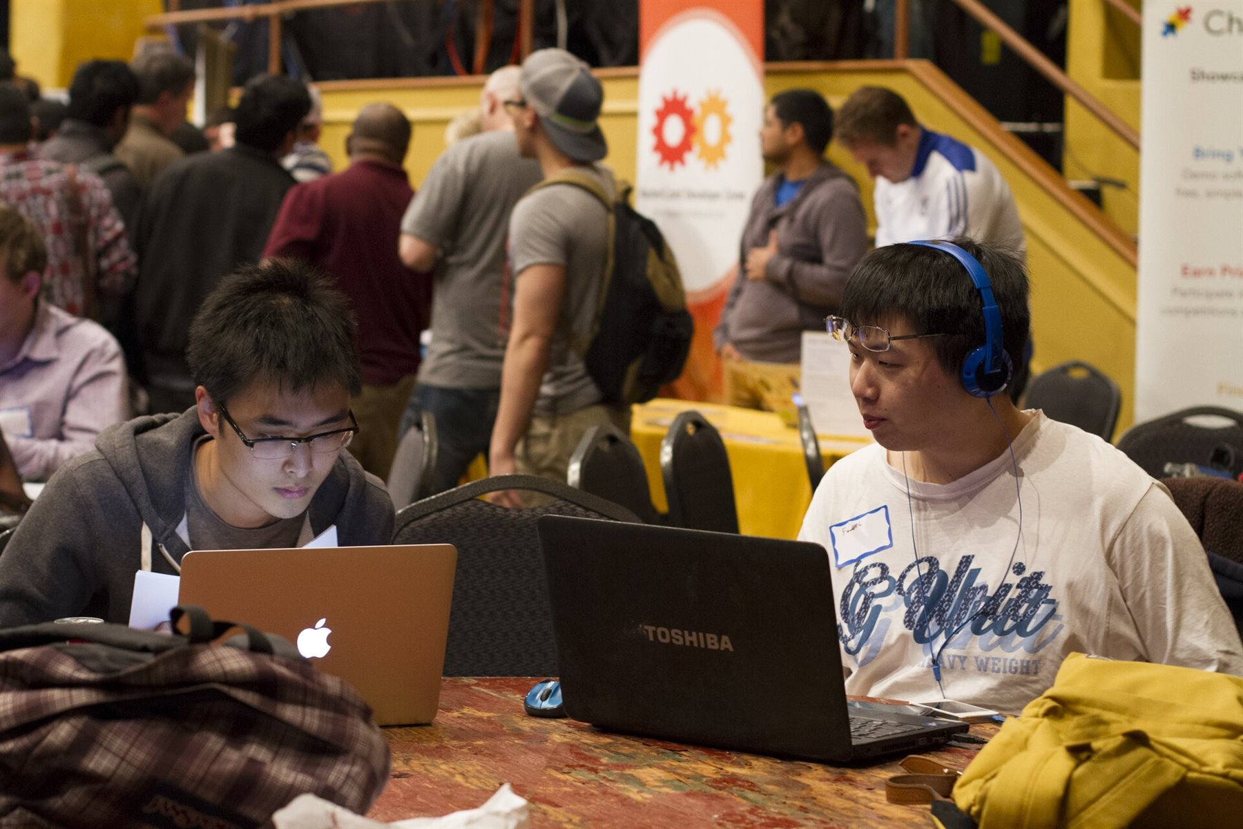 Software builders working at laptops during a hackathon, representing AI-native development platforms.